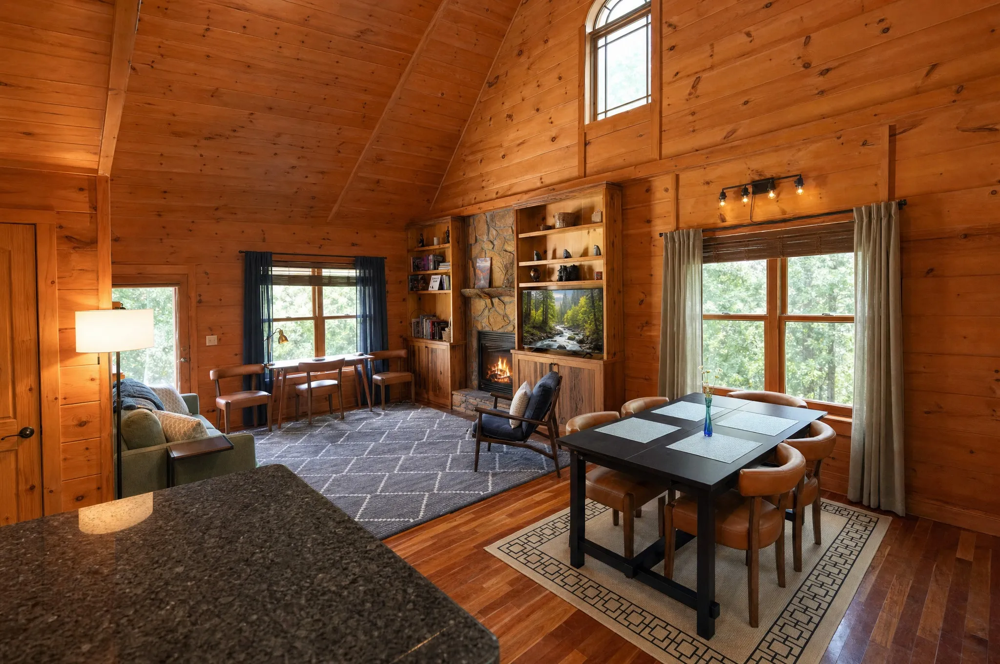 Remodeled great room with a vaulted pine ceiling, fireplace, and dining table