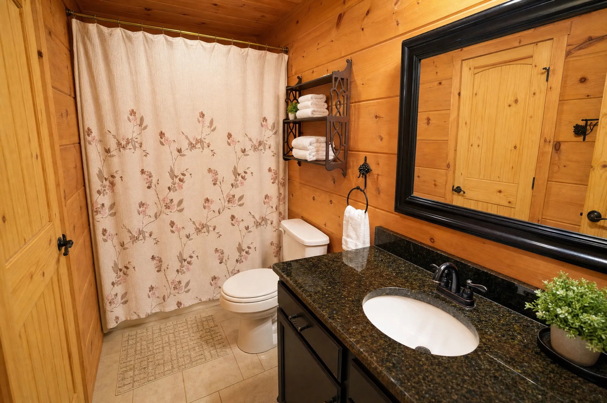 Remodeled bathroom with a floral shower curtain and dark stone vanity